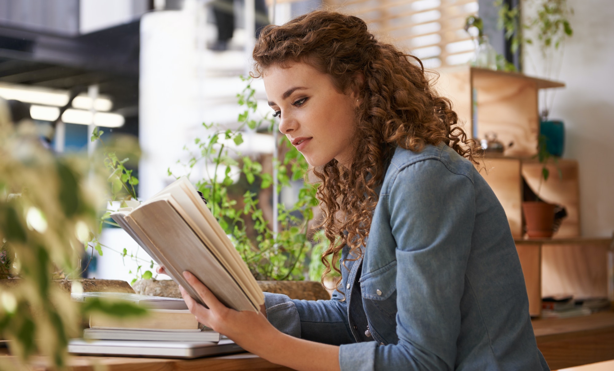 Take your hobbies wherever you go. Shot of a young woman reading a personal development book in a coffee shop.